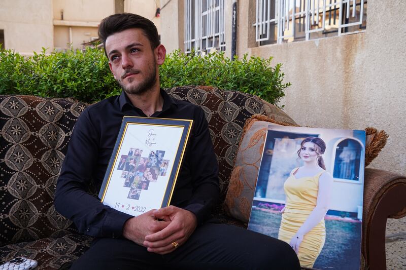 Steven Nabil, the fiance of Maryam Moatasem who died in the wedding hall fire, holds a memorial plaque containing pictures of the couple during their engagement, at his family home in Qaraqosh, northern Iraq.