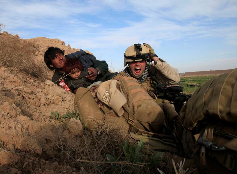 US Marine Lance Corporal Chris Sanderson, from Flemington, New Jersey shouts as he tries to protect an Afghan man and his child after Taliban fighters opened fire in the town of Marjah, in Nad Ali district, Helmand province, Afghanistan, February 13, 2010. Reuters