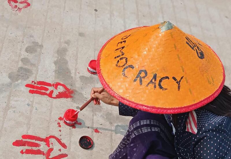 A protester paints the symbols of the three-finger salute on the ground with red paint as part of a "bleeding strike" demonstration against the military coup in Shwebo in Myanmar's Sagaing region. AFP