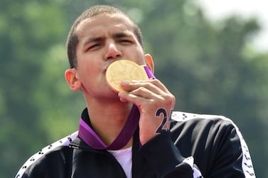 Tunisia's Oussama Mellouli (C) kisses his gold medal after winning the men's 10km open water swimming marathon at the London 2012 Olympic Games at Hyde Park in London, on August 10, 2012. Mellouli claimed victory to become the first person to win Olympic titles in both pool and open water races. AFP PHOTO / LUIS ACOSTA (Photo by LUIS ACOSTA / AFP)