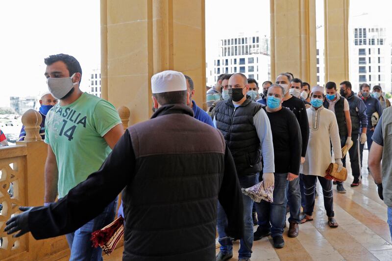 Worshippers wearing protective face masks queue to enter the Mohammed Al-Amin Mosque in the Lebanese capital Beirut's downtown district, to perform the Friday prayers during the Muslim holy month of Ramadan, after some measures that were taken by the authorities in a bid to prevent the spread of the novel coronavirus were eased, on May 8, 2020. (Photo by ANWAR AMRO / AFP)