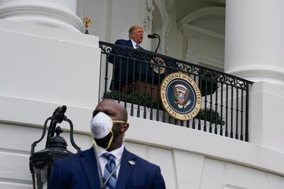 President Donald Trump speaks from the Blue Room Balcony of the White House to a crowd of supporters, Saturday, Oct. 10, 2020, in Washington. On the lower left is a member of the Secret Service wearing a face mask. (AP Photo/Alex Brandon)