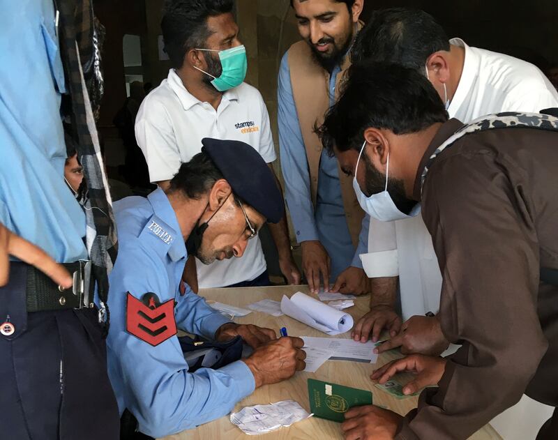 A police officer helps people to fill out forms to obtain Covid-19 vaccines. Reuters