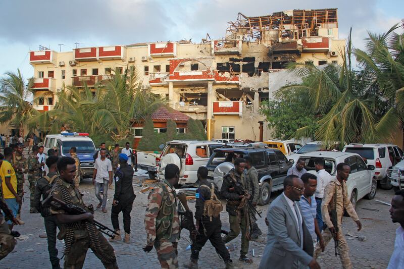Security forces and others gather in front of the hotel, which was stormed by gunmen on Friday evening. AP