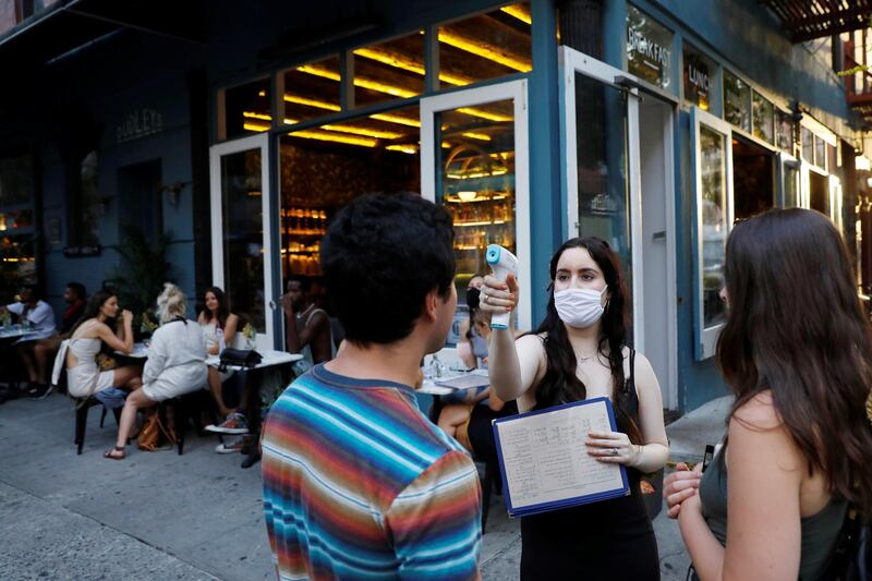 A waitress takes the temperature of customers as they arrive to eat at Dudley's as restaurants are permitted to offer al fresco dining as part of phase 2 reopening in New York City, USA. Reuters