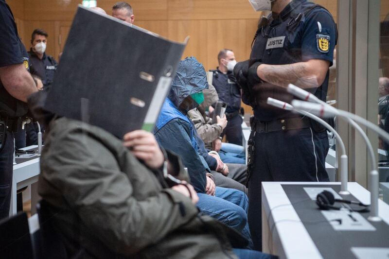 A defendant covers his face at the beginning of a trial against 11 Germans charged with belonging to a far-right organisation, that prosecutors say aimed to attack mosques, at a higher regional court in Stuttgart, Germany, April 13, 2021. REUTERS/Staff