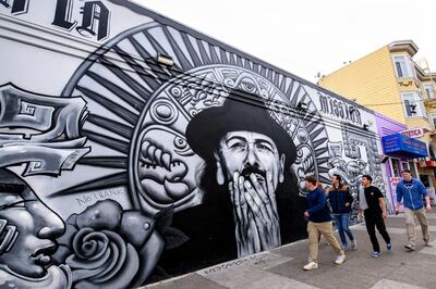 People walk by a mural dedicated to the musician Carlos Santana in the Mission District of San Francisco, California on December 23, 2017. San Francisco is a major travel destination with over 24 million visitors a year, frequenting famous landmarks like the Golden Gate Bridge, Fisherman's Wharf and Alcatraz Island. (Photo by Ronen Tivony) (Photo by Ronen Tivony/NurPhoto via Getty Images)
