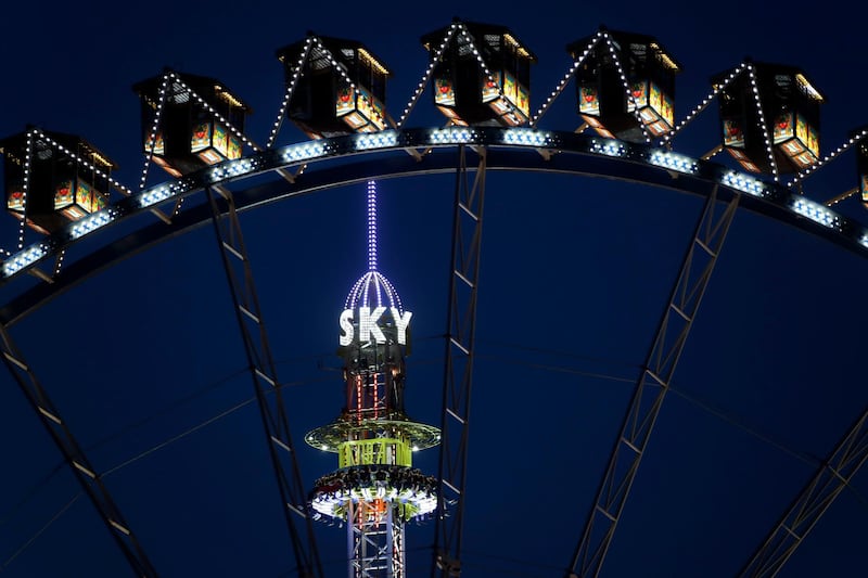 Visitors enjoy an amusement park ride behind a ferris wheel at the 184th Oktoberfest beer festival in Munich, Germany, Saturday, Sept. 21, 2017. The world's largest beer festival will be held from Sept. 16 until Oct. 3. (AP Photo/Matthias Schrader)