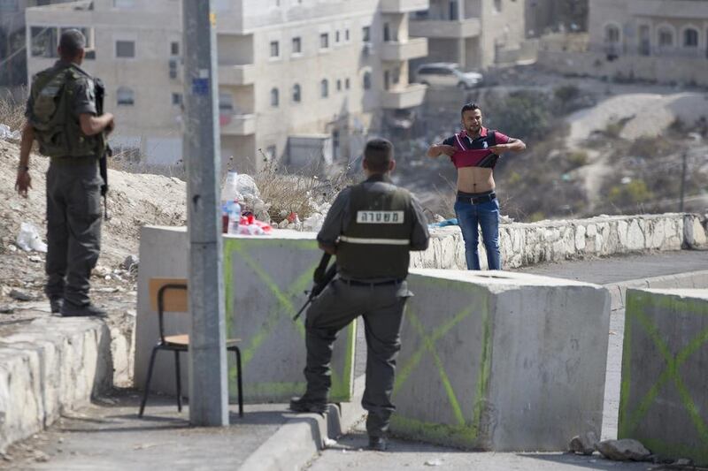Israeli border policemen order a Palestinian man to lift his shirt at a checkpoint before is allowed to exit the Arab neighborhood of Issawiyeh in Jerusalem. Ariel Schalit / AP Photo