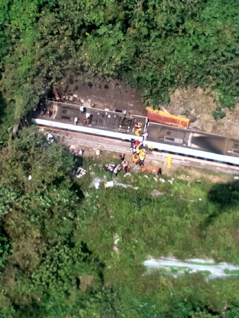 In this photo released by National Fire Agency, rescue workers are seen near the site of a partial train derailment in Toroko Gorge in Taiwan's eastern Hualien region. AP