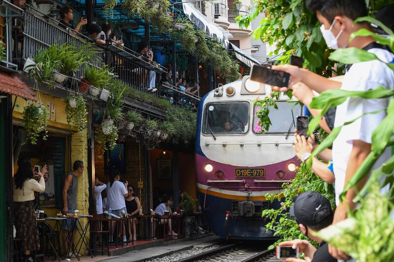 Tourists take photos of a train passing through an old residential area in central Hanoi. AFP