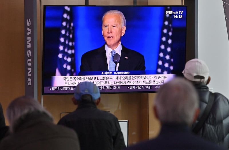 People watch a television news programme reporting on the US presidential election showing an image of US President-elect Joe Biden, at a railway station in Seoul on November 9, 2020. / AFP / Jung Yeon-je
