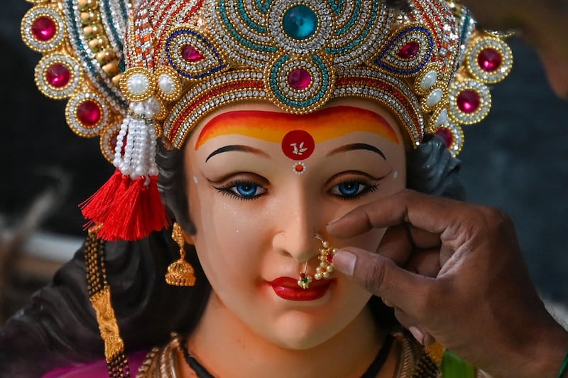 An artist adds a decorative nose ring to the idol of the Hindu goddess Durga at a workshop in Mumbai. AFP