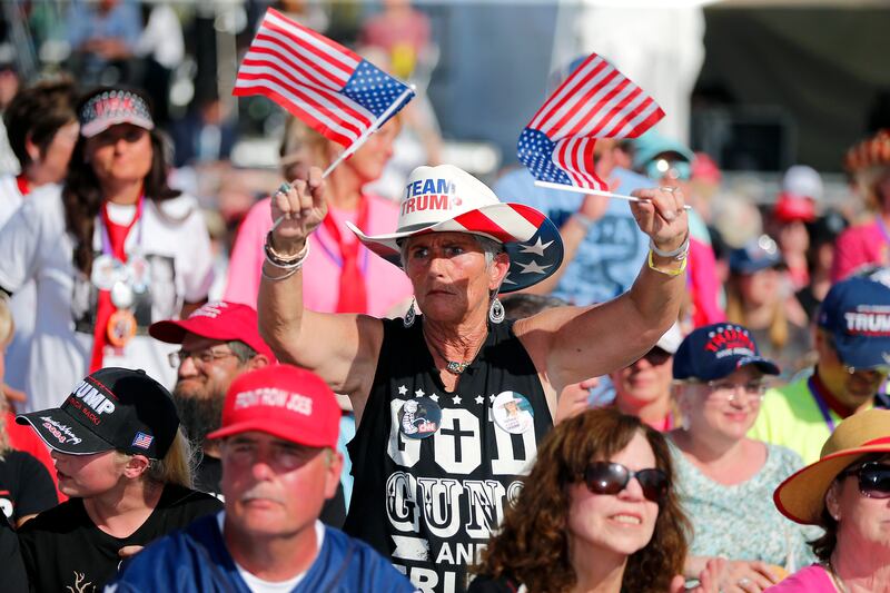 A Trump supporter wears a 'God and guns' T-shirt as she waves two American flags at the Save America rally on Saturday. AP