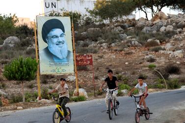 Children ride their bicycles past by a poster of Hezbollah leader Sayyed Hassan Nasrallah at the Lebanese-Israeli border village of Marwaheen, south of Lebanon, Wednesday, July 12, 2023.  An explosion near Lebanon's border with Israel slightly wounded at least three members of the militant Hezbollah group, a Lebanese security official said.  (AP Photo / Mohammed Zaatari)
