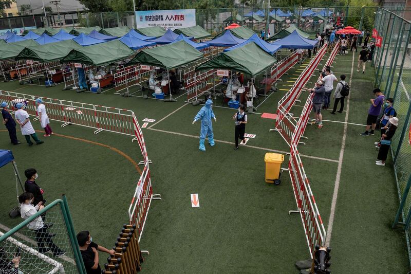 People wearing face masks gather at an outdoor area during a mass testing for the coronavirus at the Xinjiekou urban forest park testing site in Beijing. AFP