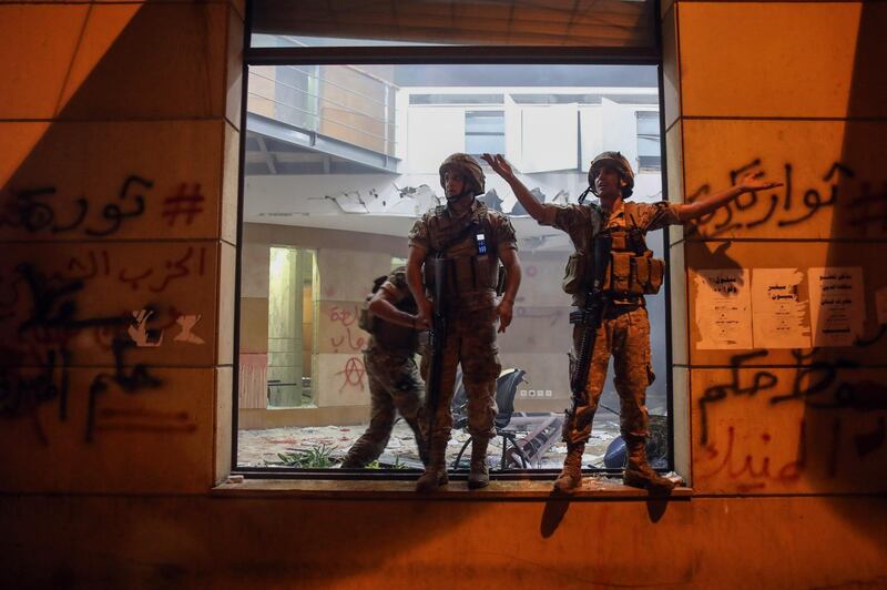 Lebanese army soldiers stand guard by a shattered window inside the Lebanese Banks Association (ABL) headquarters during a demonstration. Bloomberg