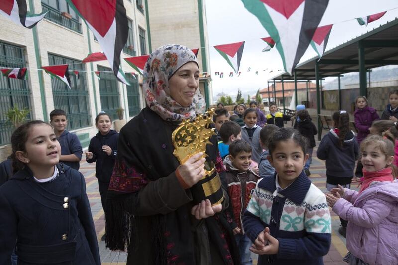 Hanan Al Hroub shows her Global Teacher trophy to Samiha Khalil students on March 20, 2016. The mother of five grew up in a refugee camp near Bethlehem. Heidi Levine for The National