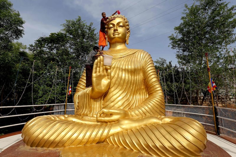 A Buddhist monk stands on the shoulder of a giant statue of Buddha to wash and decorate it on the eve of Buddha Purnima – Buddha's Birthday – in Bhopal, India. AFP