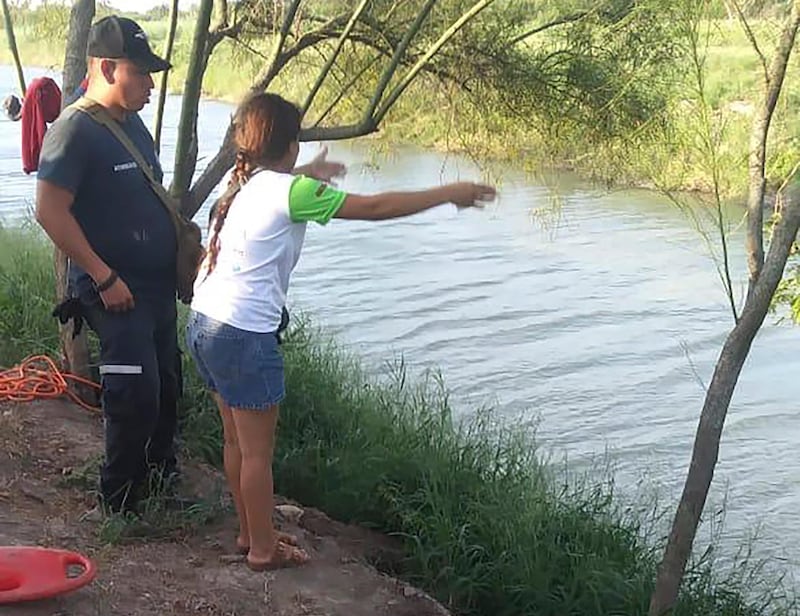 In this Sunday, June 23, 2019 photo, Tania Vanessa Ãvalos of El Salvador speaks with Mexican authorities after her husband and nearly two-year-old daughter were swept away by the current in Matamoros, Mexico, while trying to cross the Rio Grande to Brownsville, Texas. Their bodies, the toddler still tucked into her father's shirt with her arm loosely draped around him, were discovered Monday morning several hundred yards from where they had tried to cross. (AP Photo/Julia Le Duc)