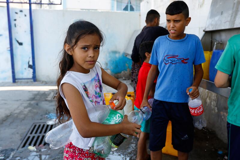 Palestinian children in Khan Younis fill bottles with water from public taps during the conflict with Israel. Reuters