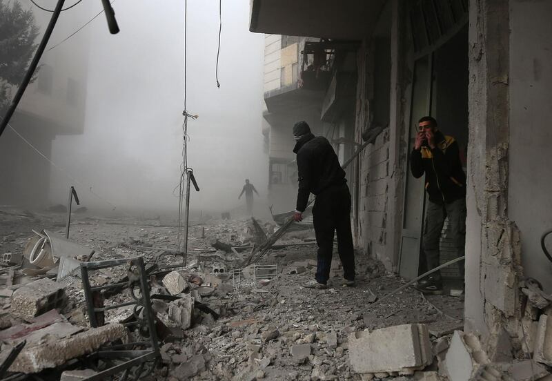 Members of the Syrian civil defence search for injured victims through the rubble of destroyed buildings in an area hit by a reported regime air strike in the rebel-held town of Hamouria, in the besieged Eastern Ghouta region. Abdulmonam Eassa / AFP