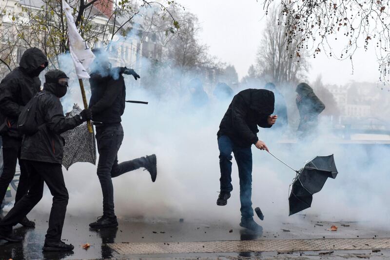 Demonstrators react as a tear gas canister lobbed by French anti-riot police officers lands at their feet during a protest in Nantes, western France. AFP