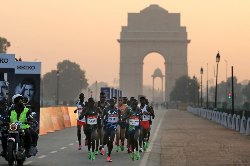 The India Gate monument is seen in the background as participants run during the Delhi Half Marathon in New Delhi on Sunday. AP