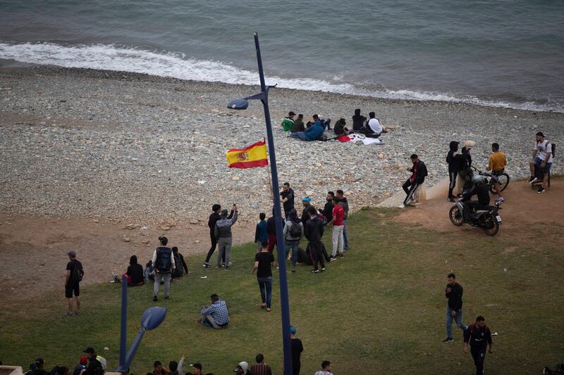 Moroccan youths wave a Spanish flag on the border with Ceuta. AP Photo