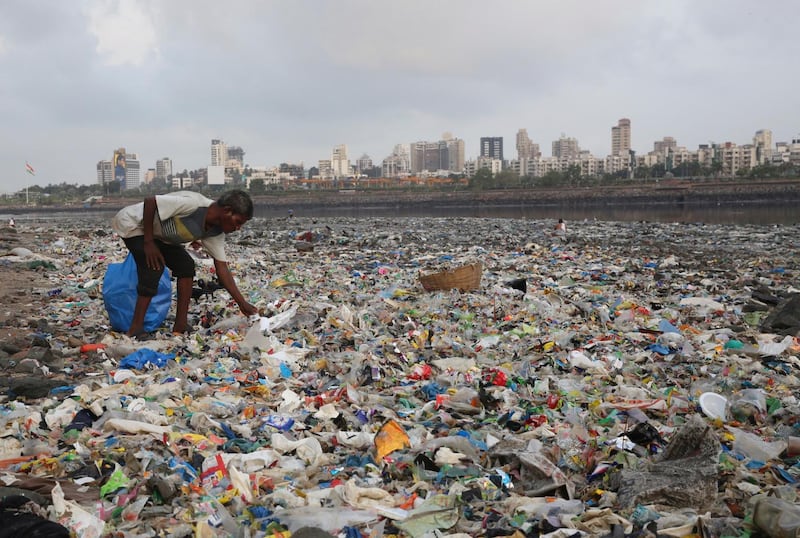 In this June 4, 2018, photo, a man collects plastic and other recyclable material from the shores of the Arabian Sea, littered with plastic bags and other garbage, in Mumbai, India. The theme for this year's World Environment Day, marked on June 5, is "Beat Plastic Pollution." (AP Photo/Rafiq Maqbool, File)