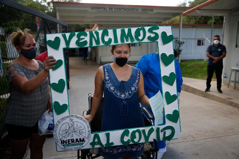 A patient discharged from the Covid-19 wing of National Institute of Respiratory and Environmental Diseases poses for a photo with a frame, brought by relatives, that reads in Spanish "We defeated COVID" hospital in Asuncion, Paraguay. AP Photo