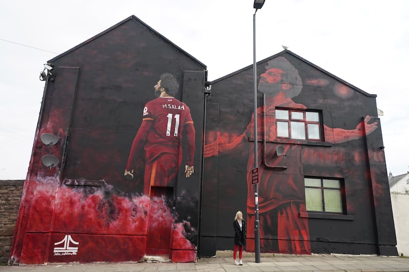 A woman poses for pictures next to a mural of Liverpool and Egypt football star Mohamed Salah outside the Anfield stadium in Liverpool, England. EPA