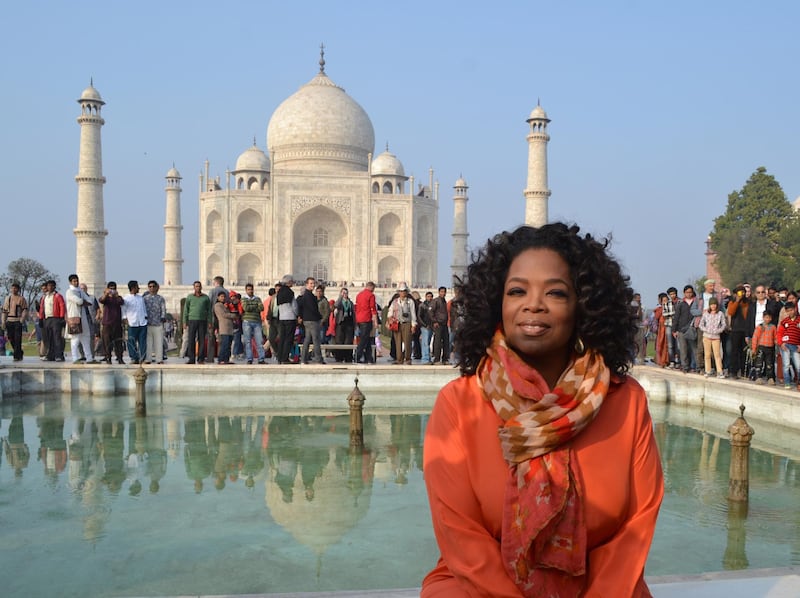 US talk show host Oprah Winfrey poses in front of the Taj Mahal on January 19, 2012. Winfrey is on her first visit to the country to film an episode of her new talk show, "Oprah’s Next Chapter", and is expected to attend a literary festival in Jaipur city. AFP PHOTO / STR (Photo by STRDEL / AFP)