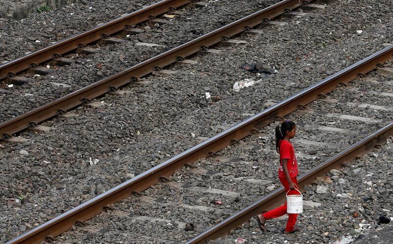 In this June 30, 2015 file photo, an Indian girl holds a can filled with water and walks past railway tracks to defecate in the open in Mumbai, India. The numbers in the government's ambitious Swachh Bharat, or Clean India, program are staggering. India's population of 1.3 billion constituted 60 percent of the world's open defecation in 2014, when Prime Minister Narendra Modi came to power, dropping to 20 percent by 2018. (AP Photo/Rajanish Kakade, File)