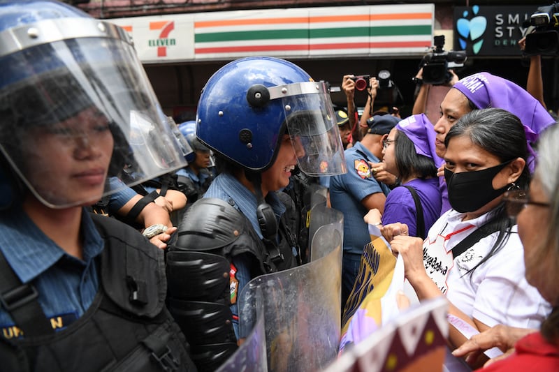 Women activists face off with riot police who blocked their protest march towards the Malacanang Palace on International Women's Day in Manila. AFP