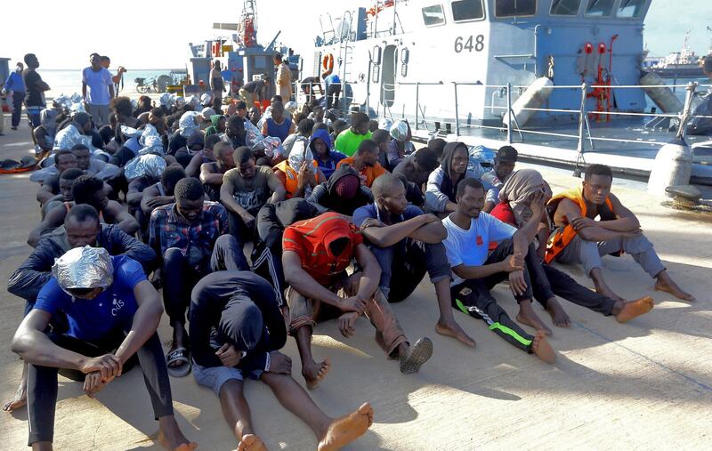 African migrants rescued from a ship off the coast of Zuwara, about 130 kilometres west of the Libyan capital Tripoli, sit at the dock at the capital's naval base on June 18, 2018. (Photo by MAHMUD TURKIA / AFP)