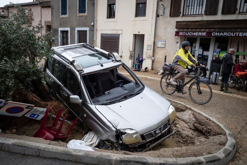 A man rides past a damaged car in the town of Villegailhenc. AP Photo