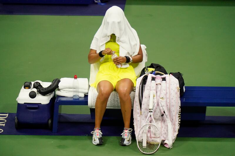 Naomi Osaka covers her head between games.  AP