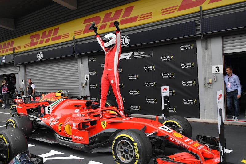 TOPSHOT - Ferrari's German driver Sebastian Vettel stands on his car in the pits after winning the Belgian Formula One Grand Prix at the Spa-Francorchamps circuit in Spa on August 26, 2018. (Photo by EMMANUEL DUNAND / AFP)