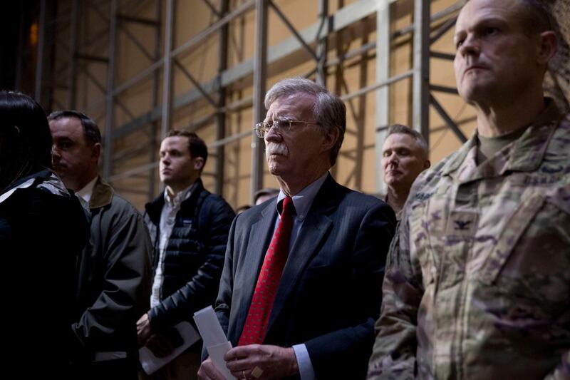 National Security Adviser John Bolton, centre, listens as President Donald Trump speaks at a hanger rally at Al Asad Air Base, Iraq. AP Photo