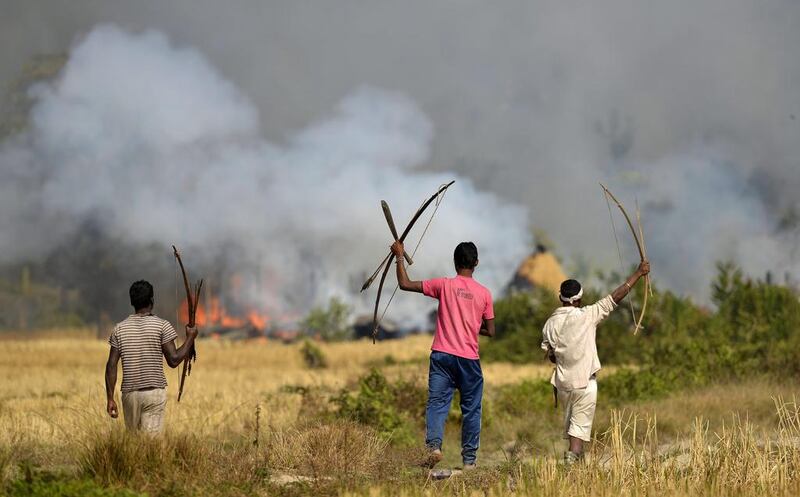 Tribal men watch houses belonging to Bodo community after they were set on fire on December 24, 2014, in retaliation for attacks by Bodo rebels a day earlier. EPA