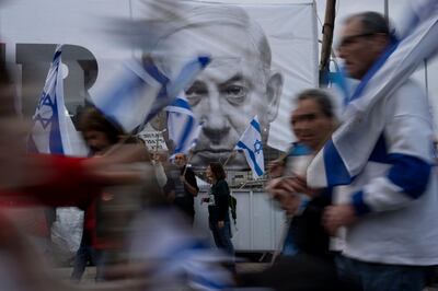 Demonstrators walk with Israel's national flags next to a banner showing Prime Minister Benjamin Netanyahu during a protest. AP Photo