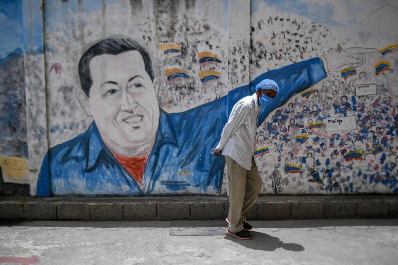 A man wearing a protective mask walks past a mural depicting Venezuela's late president Hugo Chavez at the Perez de Leon Hospital of the Petare neighbourhood, in eastern Caracas. AFP