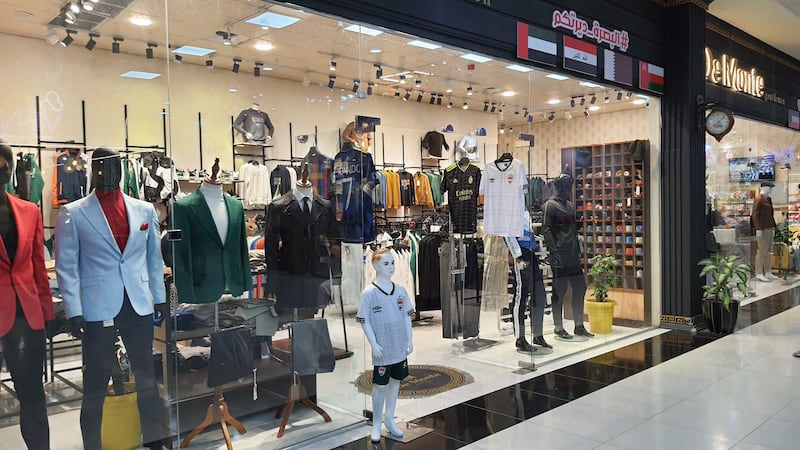 Flags of participating countries, hats, sports merchandise and souvenirs are displayed in shops and street stalls in Basra