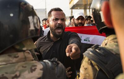 An Iraqi protestor gestures in front of security forces during a demonstration against state corruption, failing public services and unemployment, on October 2, 2019 in the southern city of Basra. Popular protests multiplied across Iraq today as thousands of demonstrators braved live fire and tear gas in rallies that have left seven dead in the past 24 hours. / AFP / Hussein FALEH

