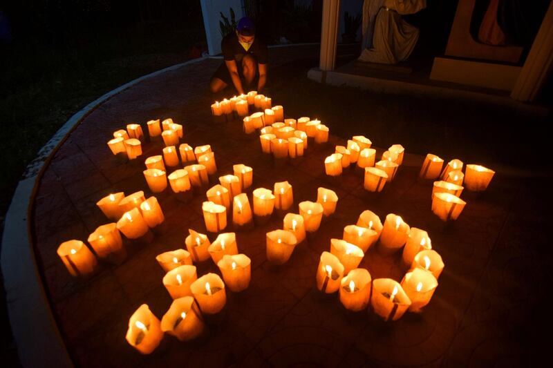 The Philippines: A volunteer arranges lit candles to read 'Fight Covid-19' during Earth Hour near a Catholic church in Borongan City, Eastern Samar province in 2020. AFP