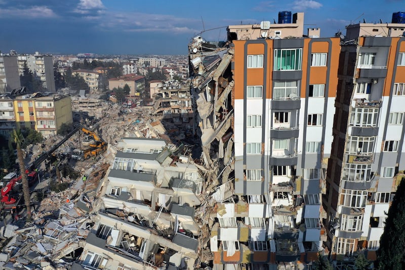 Cranes remove debris next to destroyed buildings in Antakya. AP