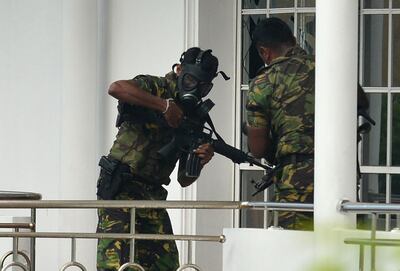 EDITORS NOTE: Graphic content / Sri Lankan Special Task Force (STF) personnel in gas masks are pictured outside a house during a raid -- after a suicide blast had killed police searching the property -- in the Orugodawatta area of the capital Colombo on April 21, 2019, following a series of blasts in churches and hotels. A string of blasts ripped through high-end hotels and churches holding Easter services in Sri Lanka on April 21, killing at least 156 people, including 35 foreigners.
 / AFP / ISHARA S.  KODIKARA
