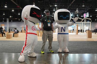 A visitor poses with mascots advertising GaNFast mobile charging technology during the CES tech show in Las Vegas. AP