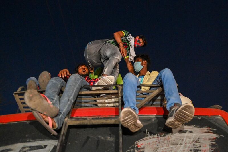 People climb on the roof of a bus at a bus station in New Delhi as India battles a record-breaking spike in Covid-19 coronavirus infections that has forced the capital into a week-long lockdown. AFP